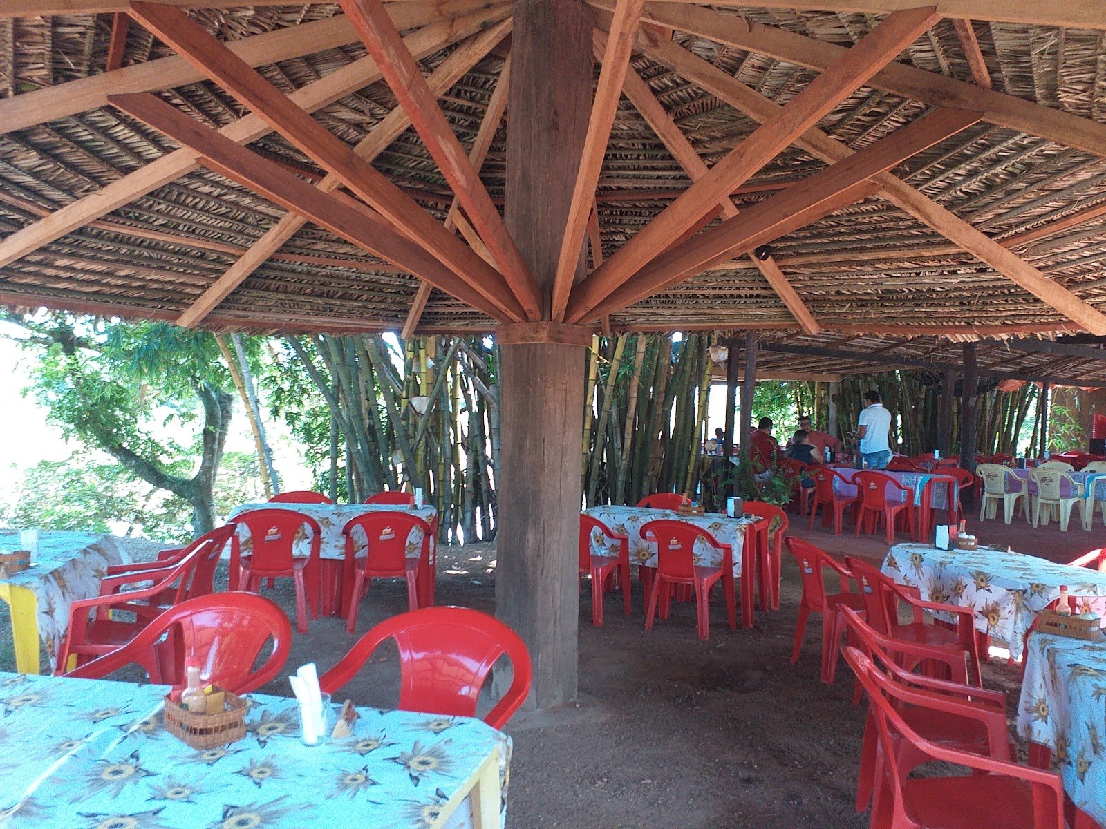 Salão coberto de palha da Bamboo's cheio de gente no almoço, entre o bambuzal, à beira do rio