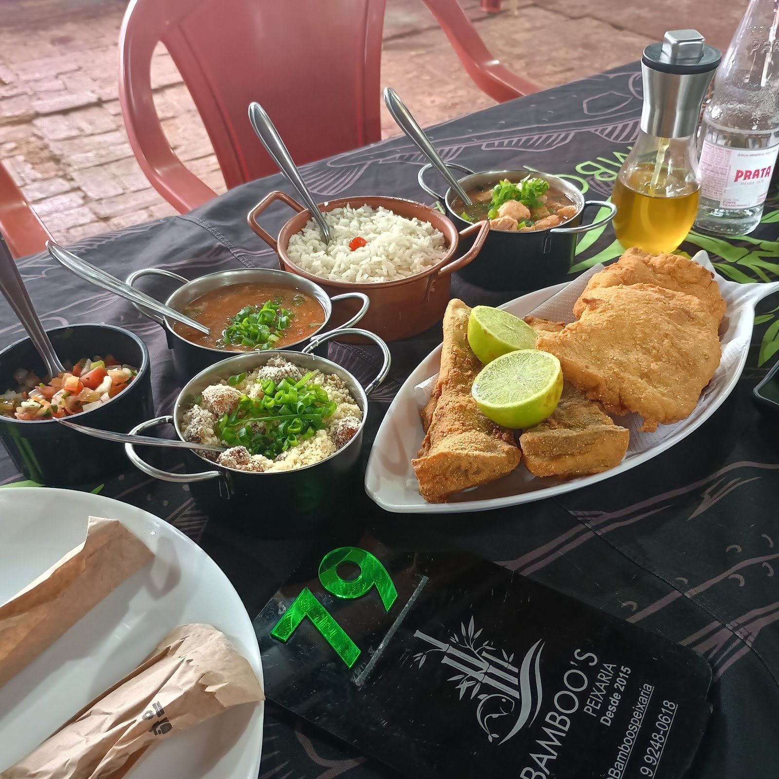 Porção de peixe frito douradinho com pirão, farofa e vinagrete servidos em panelinhas sobre a toalha da Bamboo's